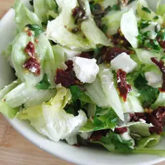 Chrupiąca surówka z sałaty lodowej z serem feta, suszonymi pomidorami i pestkami dyni.
