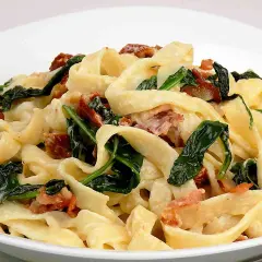 Pyszny makaron tagliatelle z kremowym sosem mascarpone, szpinakiem i chrupiącym boczkiem.