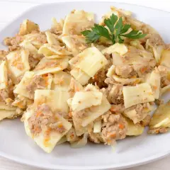 Pyszne lazanki z mielonym mięsem i warzywami, udekorowane gałązką natki pietruszki.