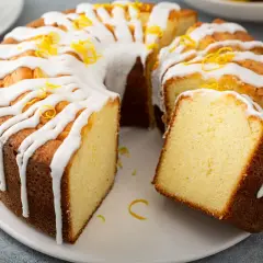 Puszysta babka cytrynowa, polana lukrem i posypana skórką cytrynową. Wygląda na najbardziej wilgotna babka na świecie!
