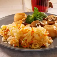 Pyszna surówka z kiszonej kapusty z marchewką, podana z duszonymi pieczarkami i kluskami śląskimi.