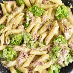 Penne z tuńczykiem i brokułami w kremowym sosie śmietanowo-serowym, przygotowane w czarnej patelni.