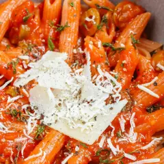 Szybki obiad z makaronem penne w sosie pomidorowym, posypany parmezanem i ziołami.
