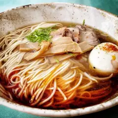 A miseczce shoyu ramen z makaronem, plastrami mięsa, bambusem i jajkiem na twardo, posypane przyprawami.