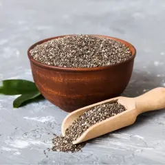 Nasiona chia jak jeść? Miseczka pełna nasion chia i drewniana łyżka z nasionami, gotowe do dodania do jogurtu lub smoothie.