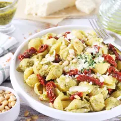 Pyszny makaron z pesto i suszonymi pomidorami, posypany parmezanem i orzeszkami pinii. Idealny na szybki obiad.