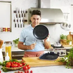 Szef kuchni prezentuje patelnie w nowoczesnej kuchni, gdzie przygotowuje się dania inspirowane kuchnią molekularną.