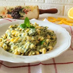 Pyszny makaron ze szpinakiem w sosie śmietanowo-serowym, udekorowany listkami bazylii. Idealny na szybki obiad.