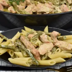Penne z kurczakiem i szparagami w kremowym sosie. Pyszne danie na talerzu i w garnku.
