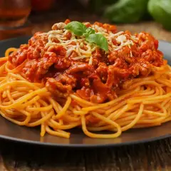 Pyszne spaghetti bolognese, idealne na prosty obiad. Makaron z bogatym sosem mięsnym, posypany serem i udekorowany bazylią.