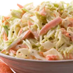 Miseczka surówki coleslaw z poszatkowanej kapusty i marchewki w kremowym sosie.