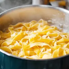 Sączący się z garnka gorący, świeży linguini, gotowy do podania z ulubionym sosem.