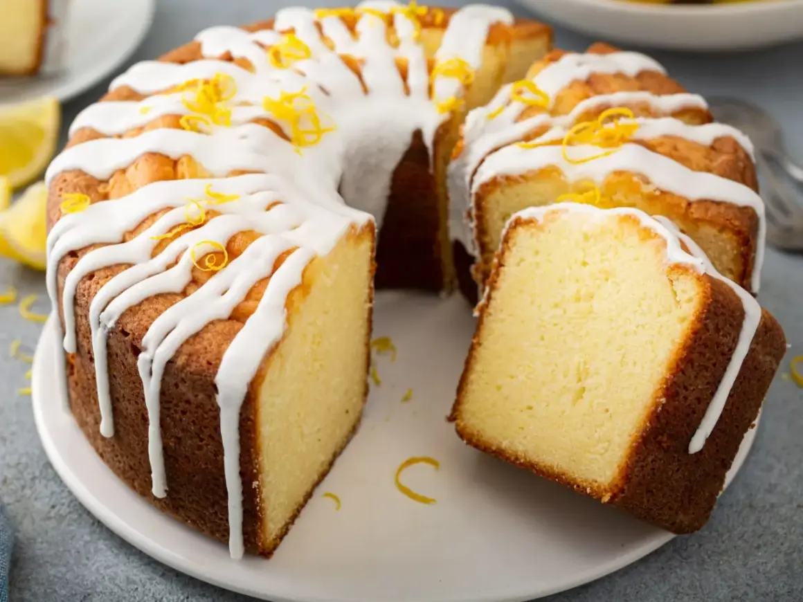 Puszysta babka cytrynowa, polana lukrem i posypana skórką cytrynową. Wygląda na najbardziej wilgotna babka na świecie!