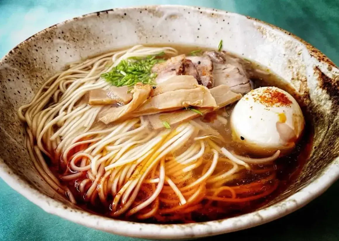 A miseczce shoyu ramen z makaronem, plastrami mięsa, bambusem i jajkiem na twardo, posypane przyprawami.