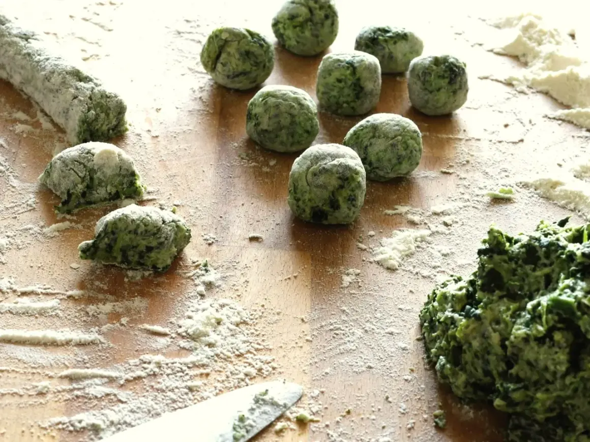Zielone, domowe gnocchi ze szpinakiem, obtoczone mąką, czekają na ugotowanie.