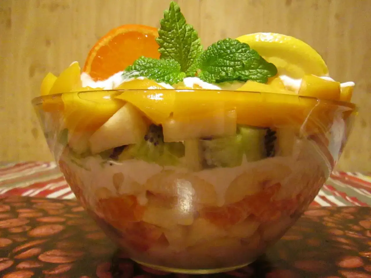Kolorowa sałatka owocowa w szklanej misce, z mango, kiwi, pomarańczą i cytryną. Idealny sos do sałatki owocowej to śmietanka z miętą.