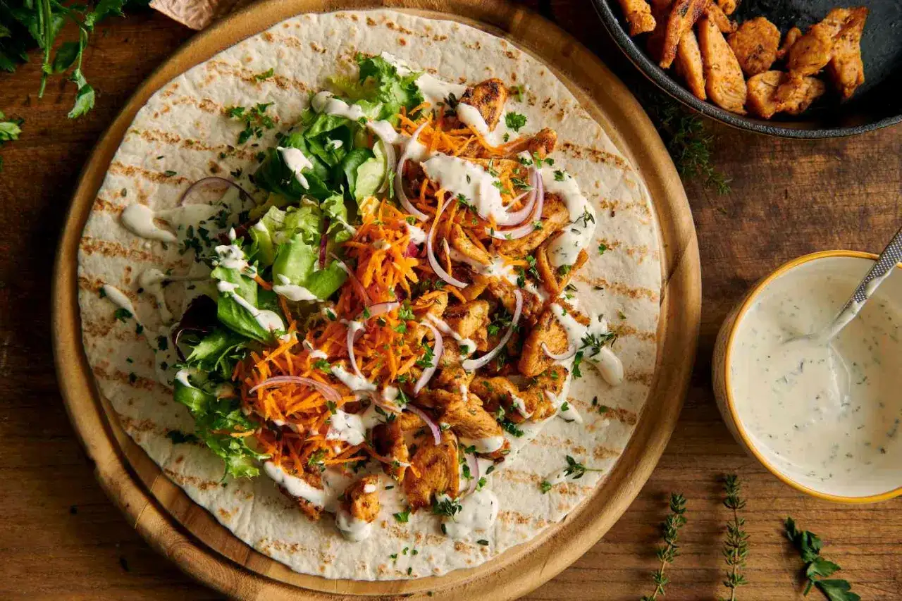 Pyszny kebab na tortilli z kurczakiem, warzywami i kremowym sosem do kebaba.